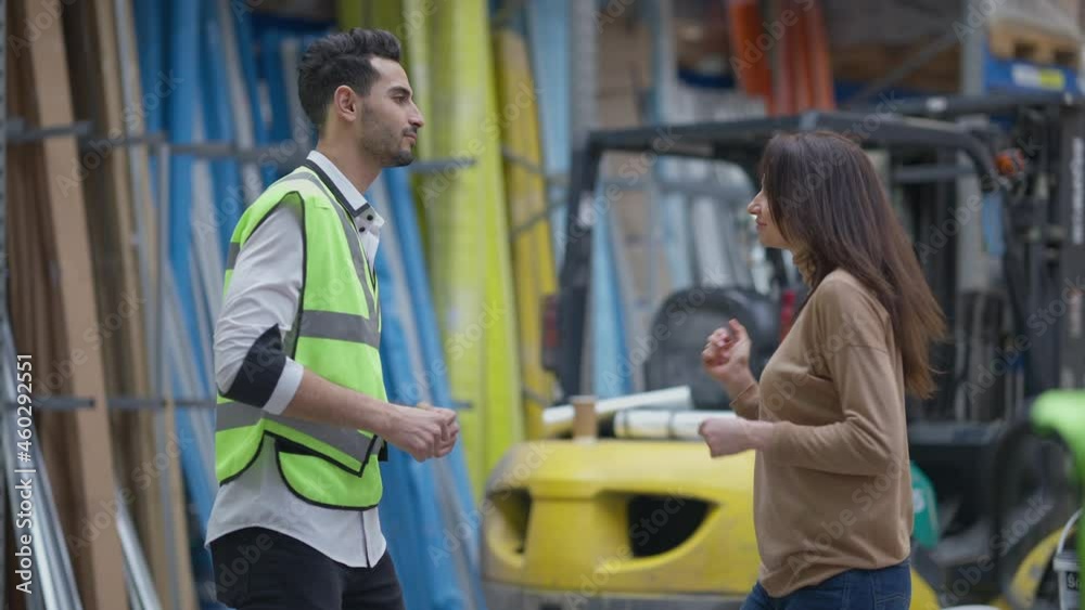 Satisfied cheerful Middle Eastern man in uniform and Caucasian woman dancing in warehouse indoors smiling. Medium shot portrait of happy joyful employee and freight agent rejoicing indoors in storage Satisfied cheerful Middle Eastern man in uniform and Caucasian woman dancing in warehouse indoors smiling. Medium shot portrait of happy joyful employee and freight agent rejoicing indoors in storage