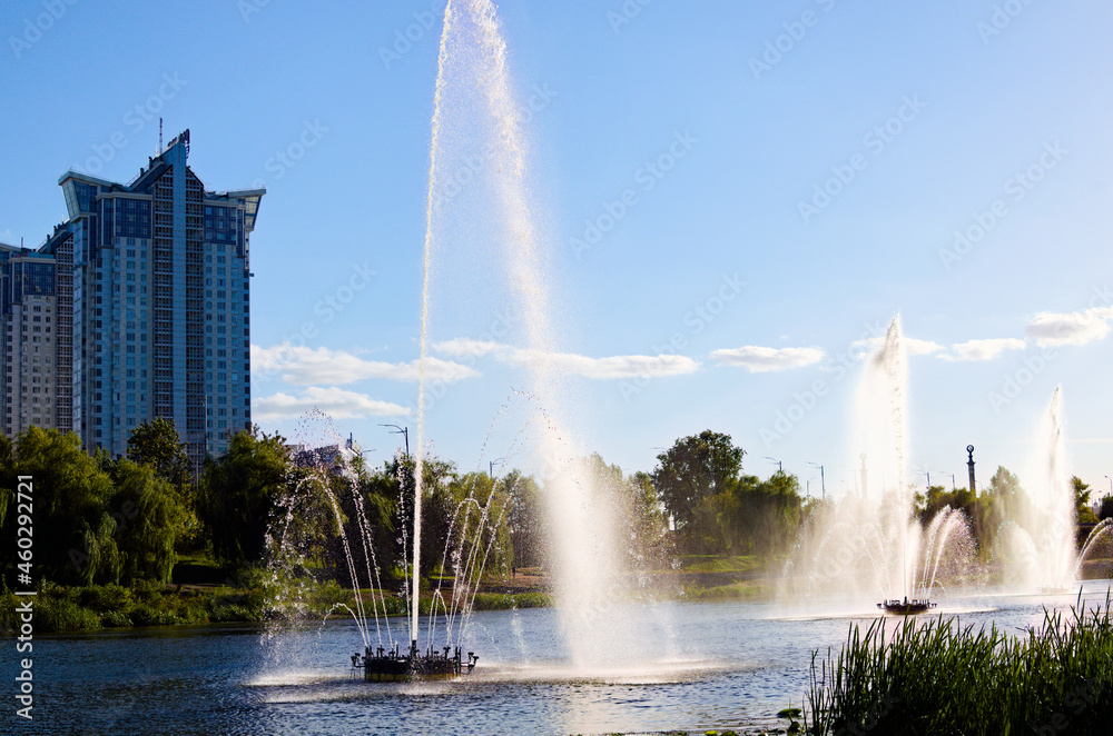 Scenic autumn landscape of fountain in the city channel near Rusanovka neighborhood at sunny day. New high-rise fashionable houses. Concept of modern architecture from glass, steel and concrete