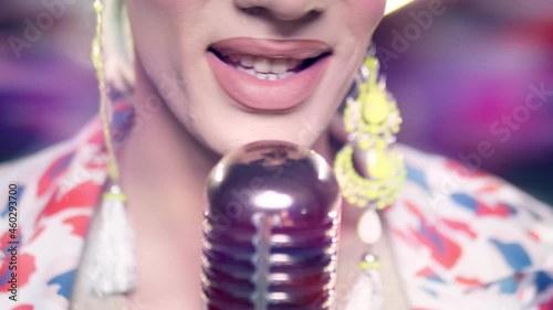 close-up of lips. male travesty artist singing into microphone on stage in safita light.