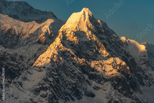 Sunset light shines on snow covered peaks in the Alaska Range of