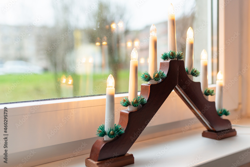 Advent electric candles on window sill.electrical advent candles by the  window with urban blurred city buildings view. Stock Photo | Adobe Stock