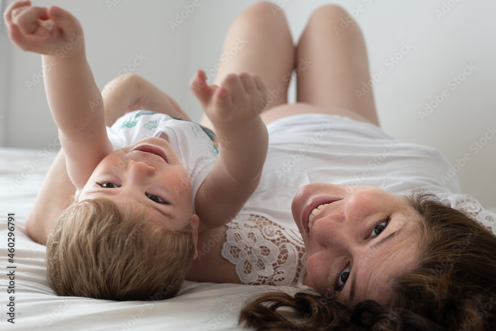 Madre embarazada sonriendo mostrando su panza y jugando con su hijo