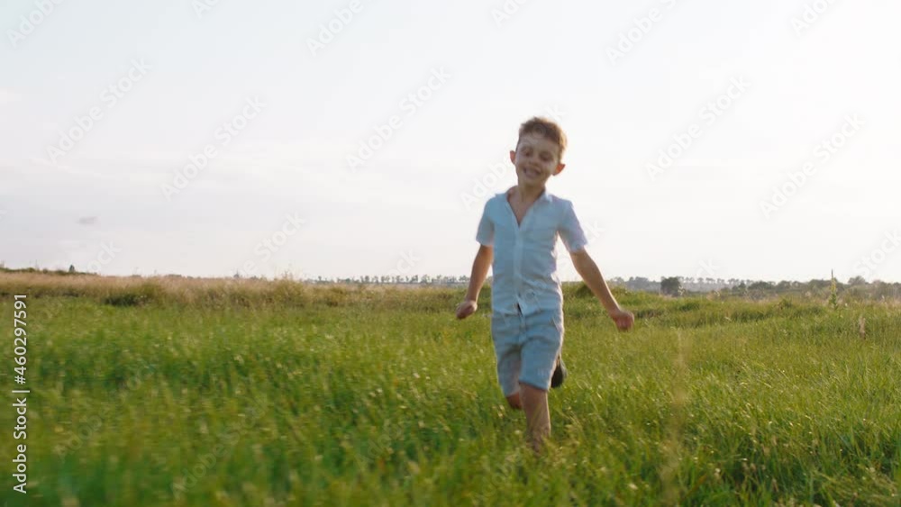 Charismatic cute boy with a perfect large smile at nature in the middle of a large field running fast through the grass in front of the camera Charismatic cute boy with a perfect large smile at nature in the middle of a large field running fast through the grass in front of the camera