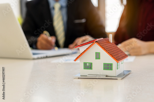 Real estate professionals and clients discussing home purchases, insurance or real estate loans. Home sales agents sit at the office with new homebuyers in the office.
