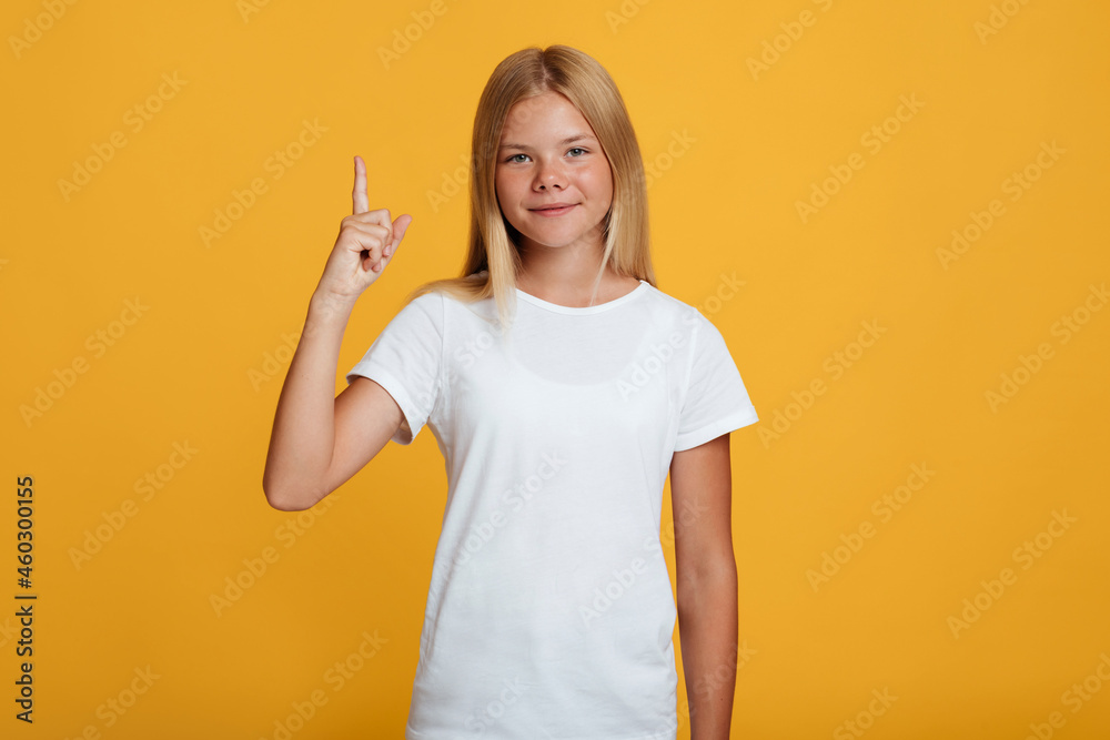 Smiling confident cute teen blonde lady in white t-shirt showing thumb up to copy space Smiling confident cute teen blonde lady in white t-shirt showing thumb up to copy space