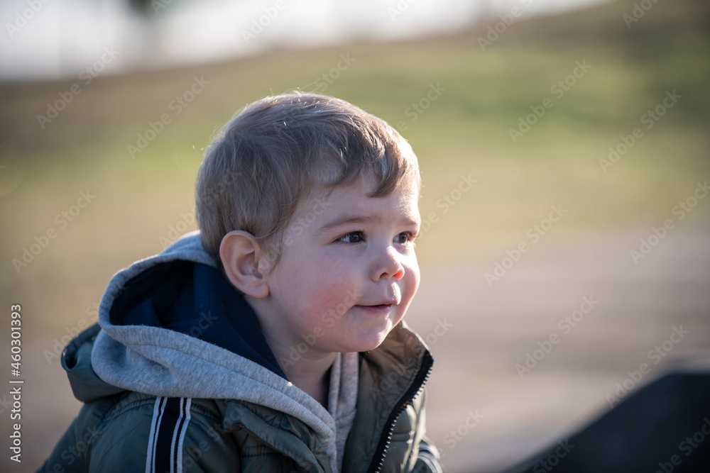Niño rubio con campera jugando en el parque en invierno Niño rubio con campera jugando en el parque en invierno