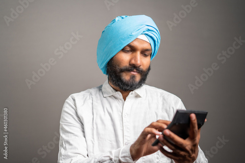 studio shot of Young sikh man seriously thinking and calculating tax or financial expenses on calculator © WESTOCK