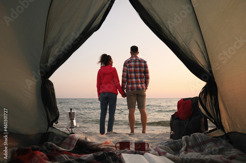 Couple near sea at sunset, view from camping tent