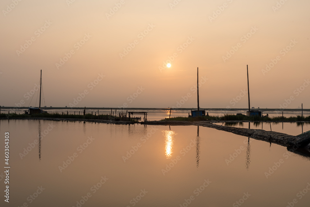 At sunrise in the morning, the sea water reflects the fishing boat