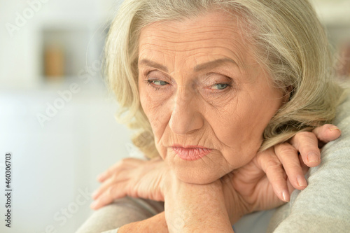 Portrait of sad senior woman at home with phone