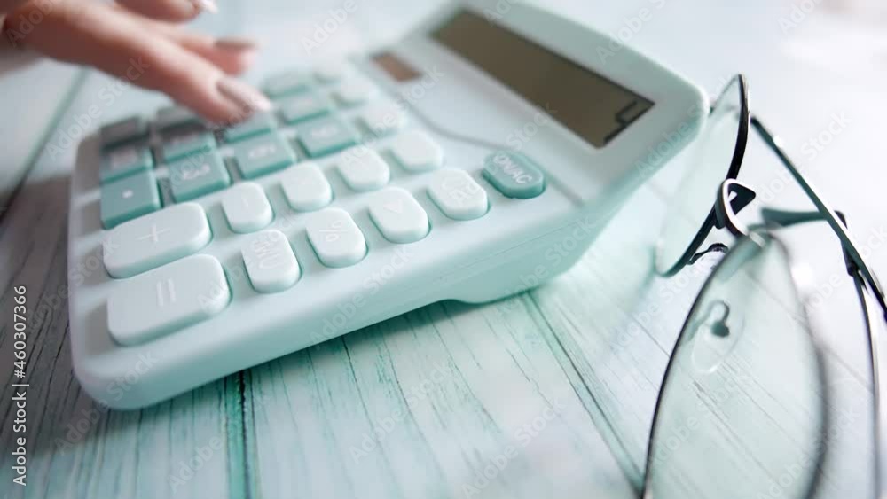 A woman is calculating her expenses for a month. Payment of taxes and payments. Financier or accountant is working. Business accounting or investment and budget planning or savings money concept. A woman is calculating her expenses for a month. Payment of taxes and payments. Financier or accountant is working. Business accounting or investment and budget planning or savings money concept.