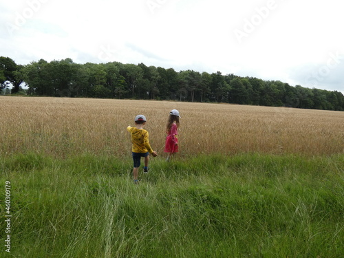 Two white kids walking through farm fields, summer time in England