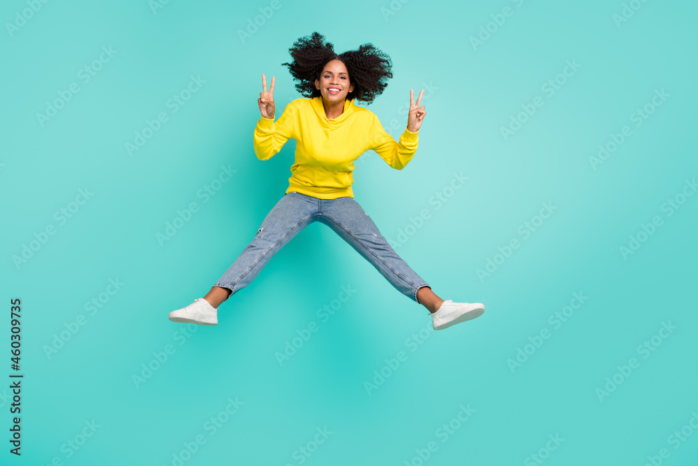 Full length body size view of nice funky cheerful girl jumping showing v-sign isolated over bright teal turquoise color background