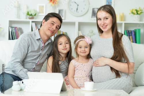 happy pregnant woman with husband and daughters
