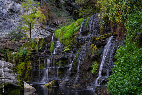 black stone wall with waterfalls falling between the forest and vegetation, rupit catalonia, spain