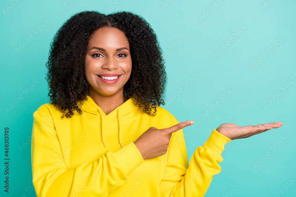 Photo portrait woman showing copyspace on palm smiling isolated bright teal color background Photo portrait woman showing copyspace on palm smiling isolated bright teal color background