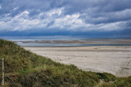 dramatic clouds on the beach in denmark between the dunes