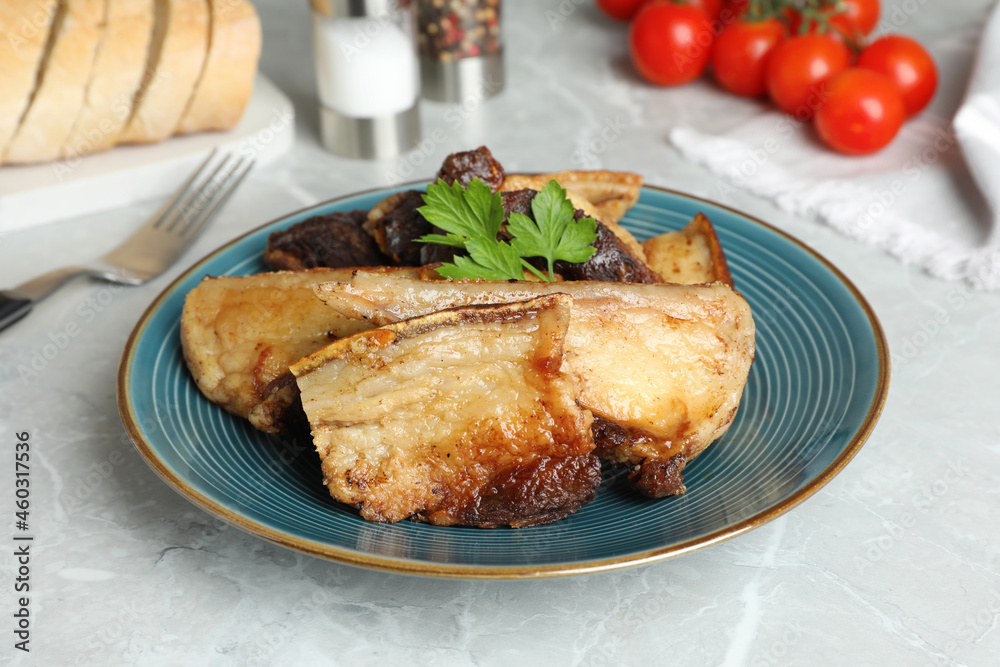 Tasty fried pork lard with parsley on light table Tasty fried pork lard with parsley on light table