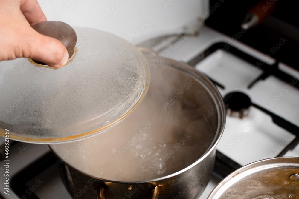 An old saucepan with boiling water and an open lid.