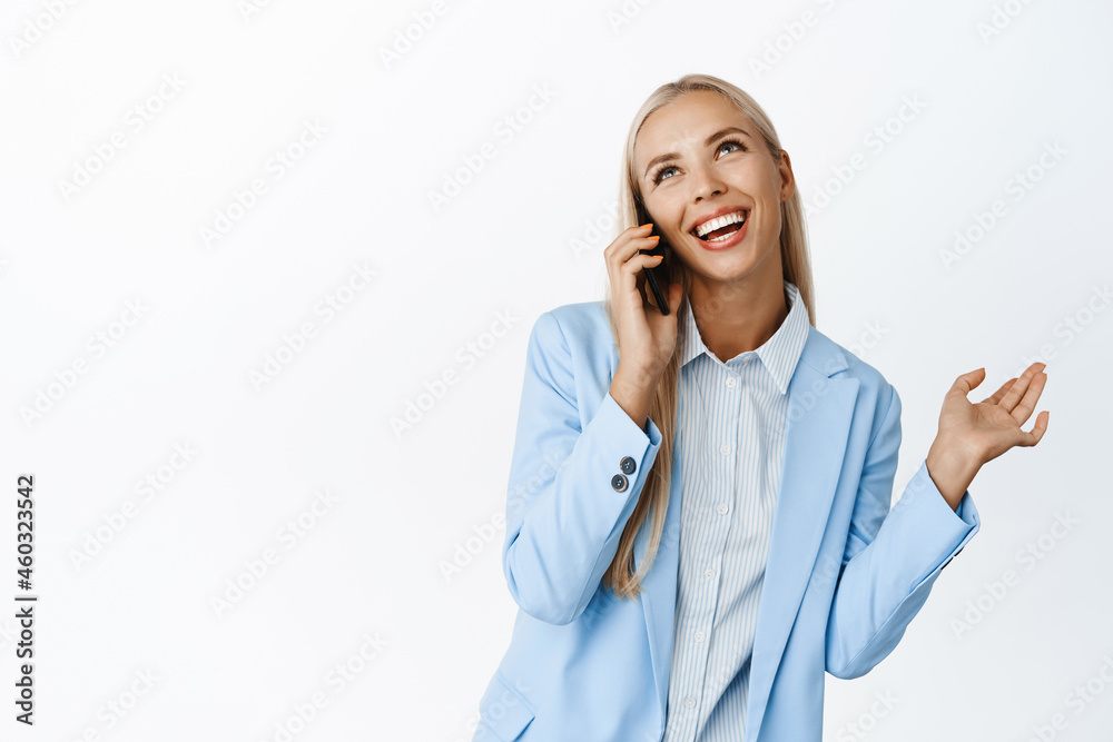 Talkative cute businesswoman talking on mobile phone, smiling and having happy conversation, standing over white background Talkative cute businesswoman talking on mobile phone, smiling and having happy conversation, standing over white background