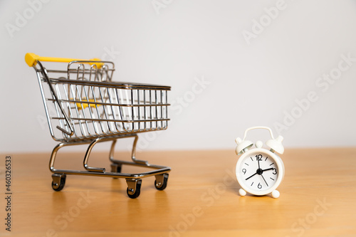Shopping time - shopping cart and white vintage alarm clock
