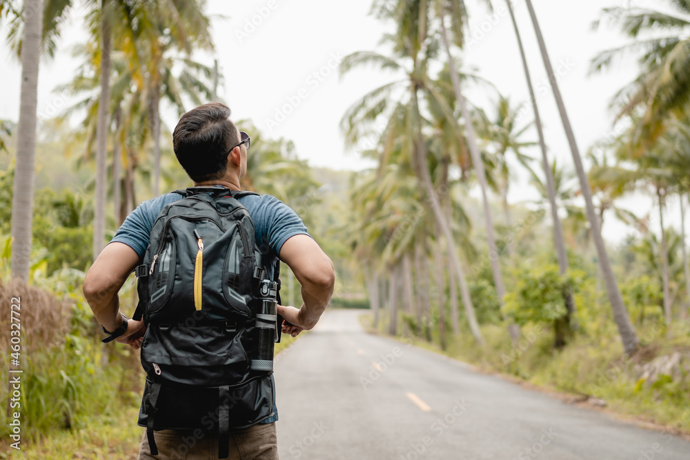 Man with backpack walking road in forest.