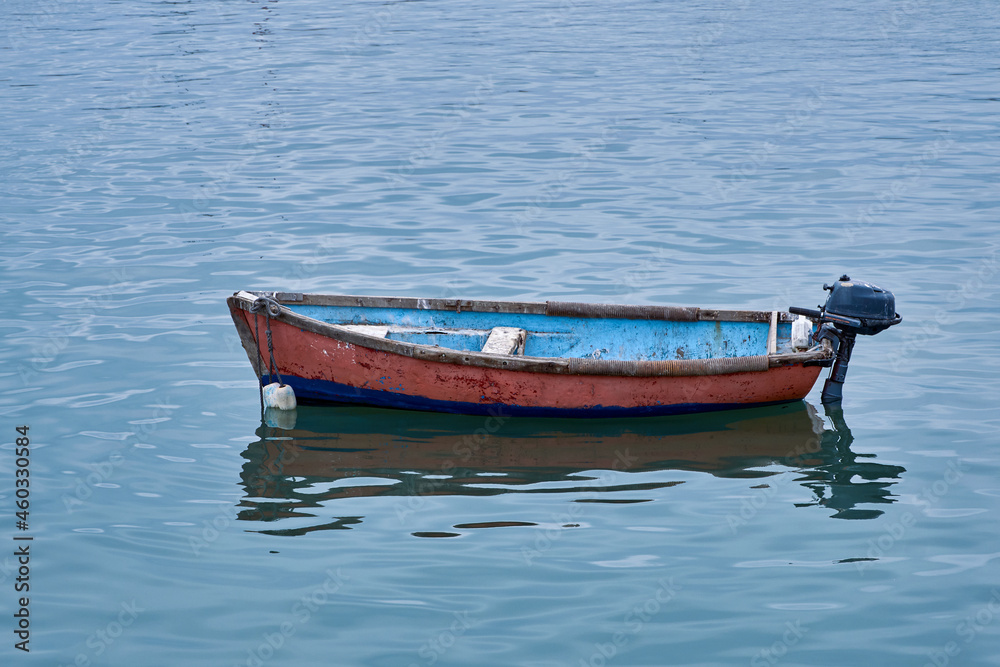 Small wooden fishing boat with one outboard motor in clear blue water. Small wooden fishing boat with one outboard motor in clear blue water.