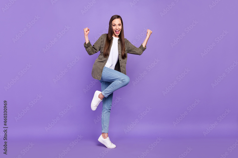 Full size photo of smiling positive young female raise fists in victory success triumph isolated on violet color background Full size photo of smiling positive young female raise fists in victory success triumph isolated on violet color background