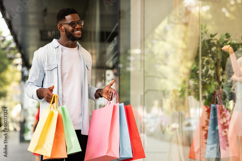 Black man with shopping bags looking at mall