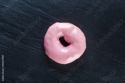 Glazed donut with strawberry, raspberry flavor on a stone background