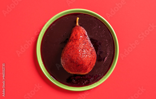 Red wine poached pear on the plate, above view.