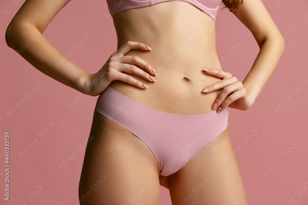 Beautiful body of young slim woman in lingerie, panties isolated on pink studio background. Natural beauty concept.