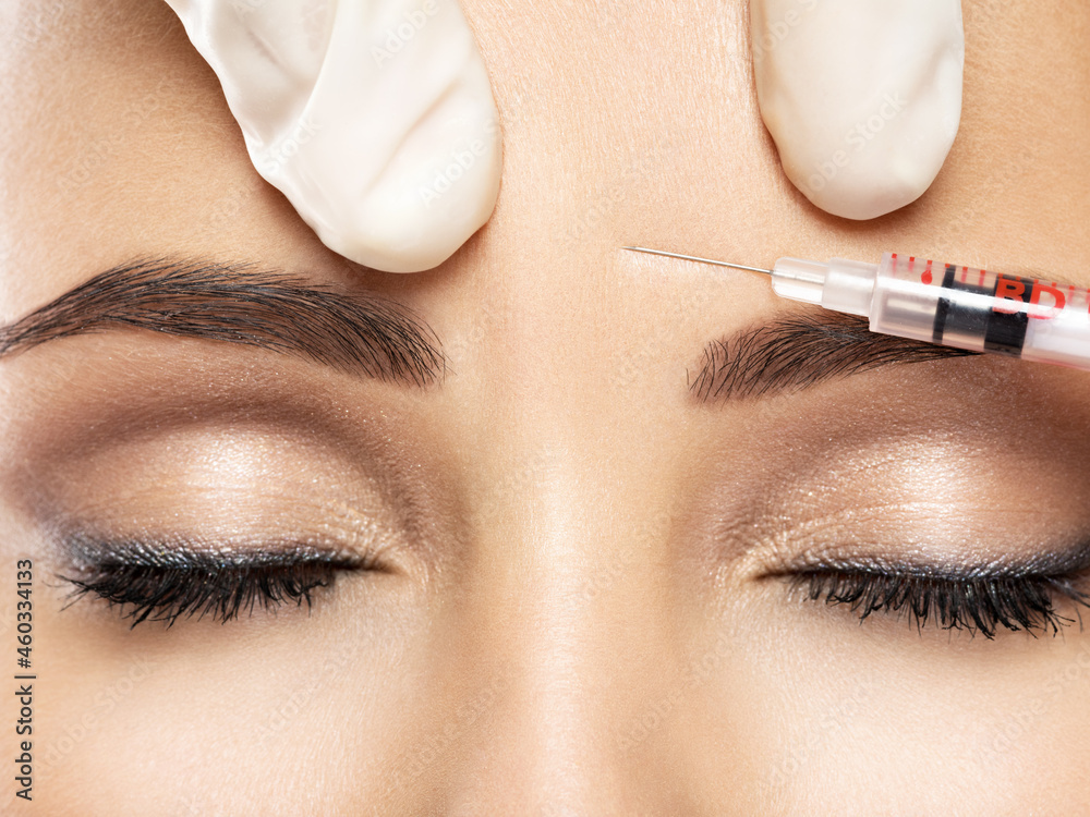  woman getting cosmetic botox injection in forehead