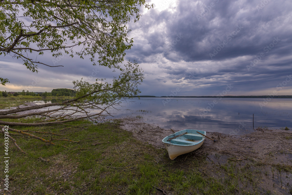 Evening landscape on the lake in early spring. The dramatic sky is reflected in the water. Evening landscape on the lake in early spring. The dramatic sky is reflected in the water.