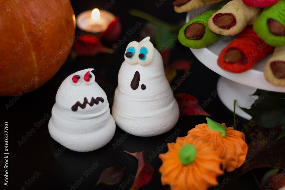 Halloween ensemble featuring delightful meringue phantoms, a classic pumpkin, and a collection of tempting treats illuminated by ambient light.