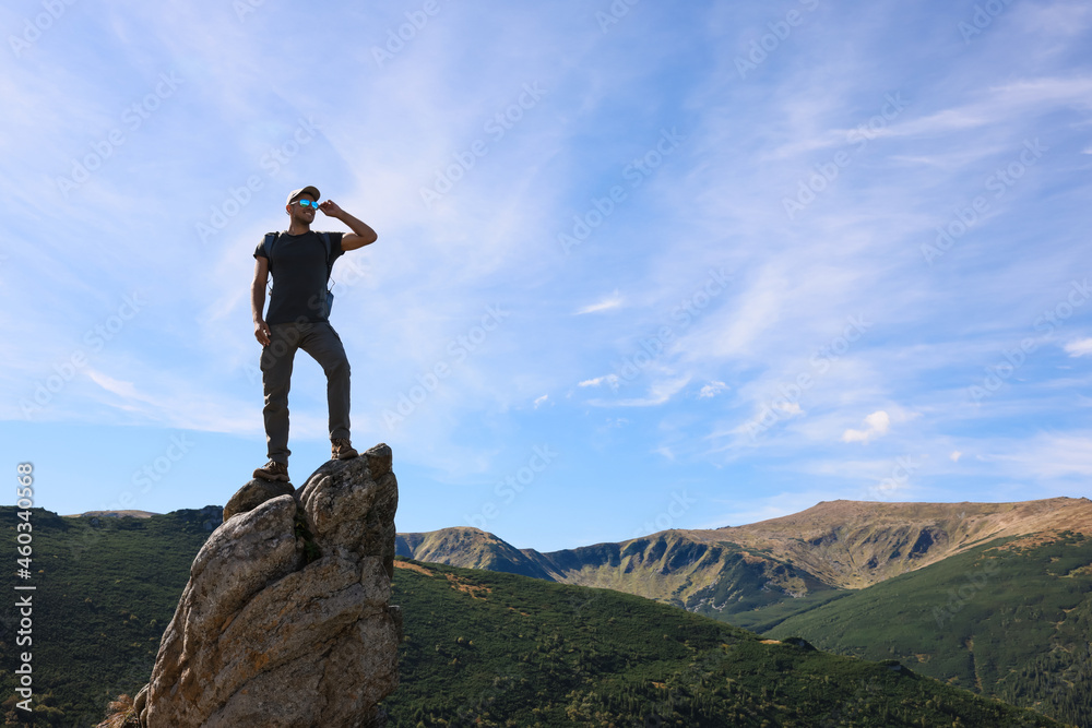 Man enjoying picturesque view on cliff in mountains. Space for text