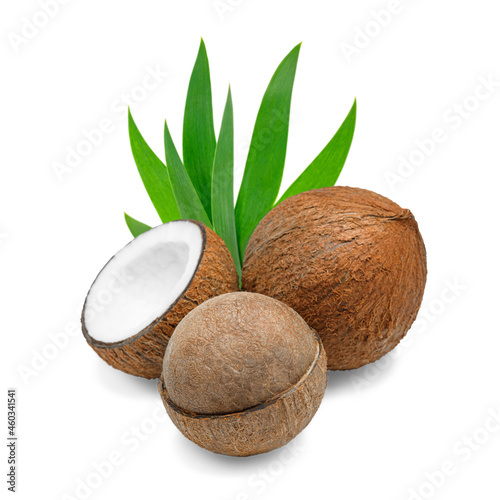three coconuts with green leaves lying next to each other on a white isolated background.