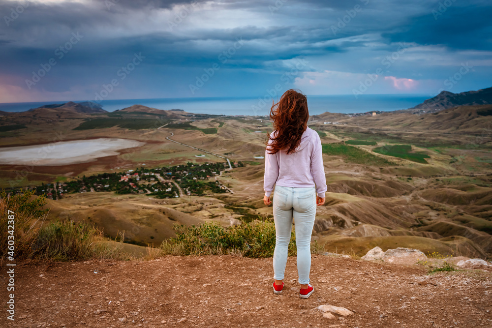 Young woman on top of a mountain at dawn with amazing mountain scenery and valley