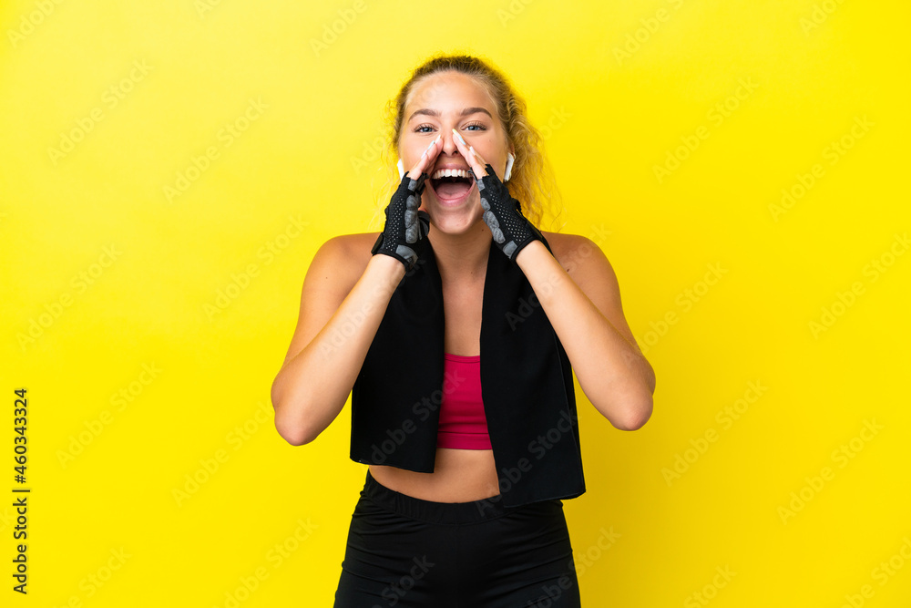 Sport woman with towel isolated on yellow background shouting and announcing something Sport woman with towel isolated on yellow background shouting and announcing something