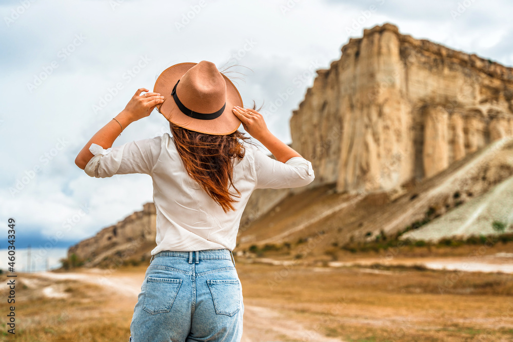 A young woman in a hat at the foot of a White Rock in the Crimea. A beautiful wild west scene with a charming adventurous traveler
