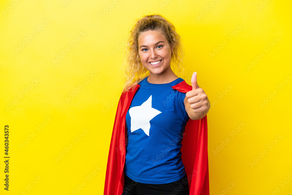 Girl with curly hair isolated on yellow background in superhero costume with thumb up Girl with curly hair isolated on yellow background in superhero costume with thumb up