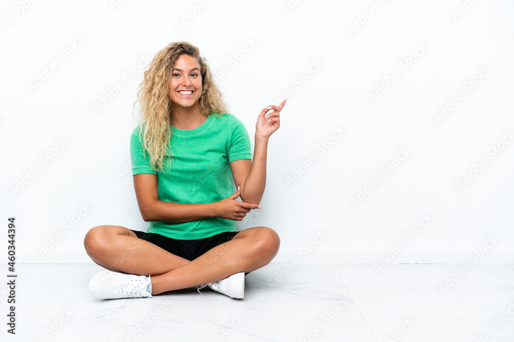 Girl with curly hair sitting on the floor pointing finger to the side Girl with curly hair sitting on the floor pointing finger to the side