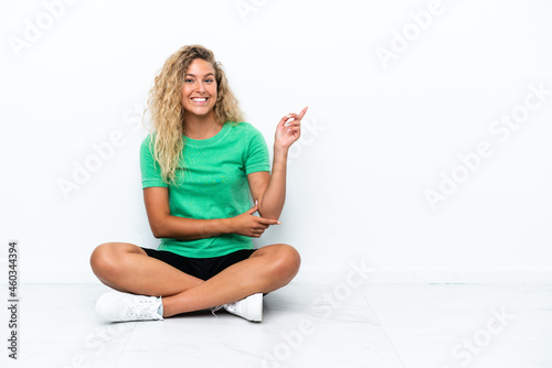 Wallpaper Mural Girl with curly hair sitting on the floor pointing finger to the side Torontodigital.ca