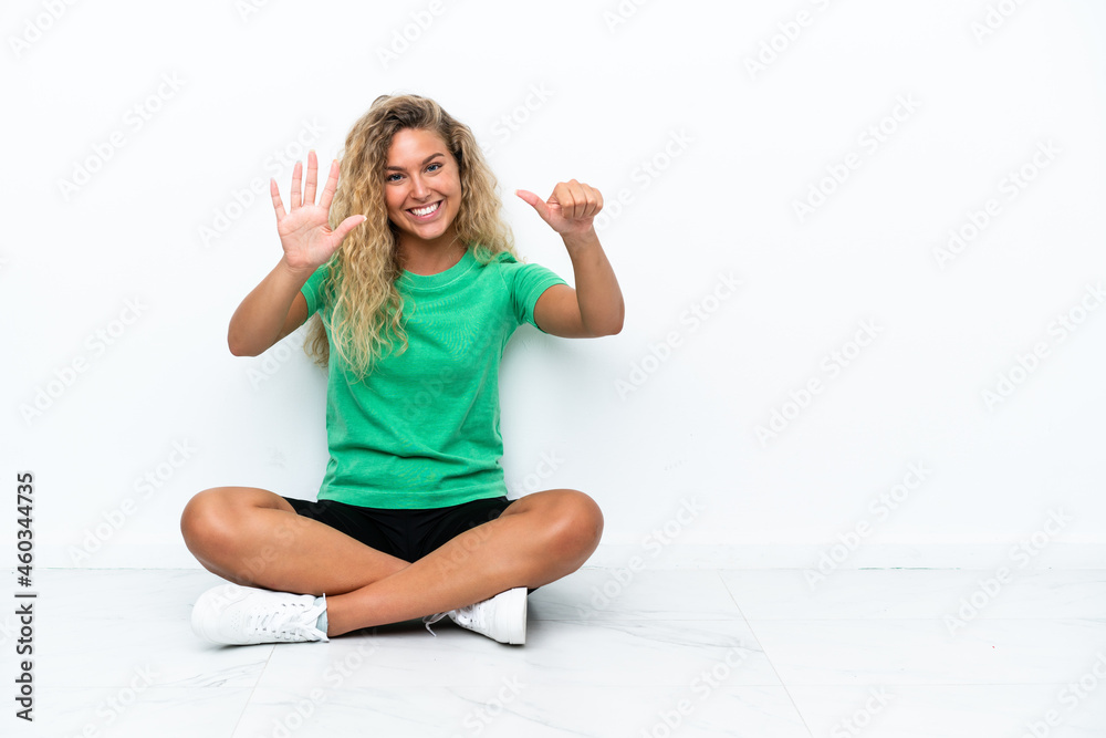 Girl with curly hair sitting on the floor counting six with fingers Girl with curly hair sitting on the floor counting six with fingers