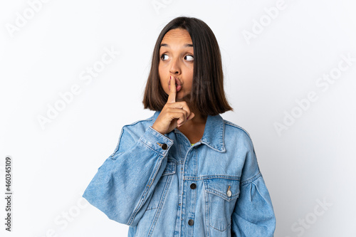 Young latin woman isolated on white background showing a sign of silence gesture putting finger in mouth