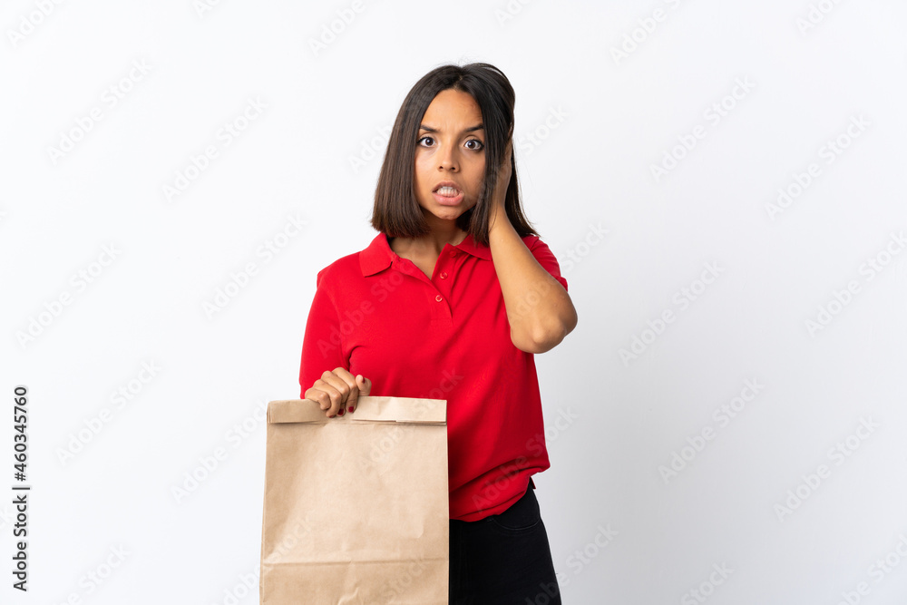 Young latin woman holding a grocery shopping bag isolated on white background frustrated and covering ears Young latin woman holding a grocery shopping bag isolated on white background frustrated and covering ears