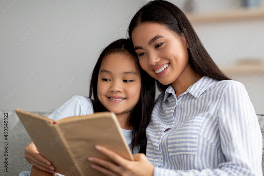 Family stay home hobbies. Happy asian mother and her cute daughter reading book together at home Family stay home hobbies. Happy asian mother and her cute daughter reading book together at home