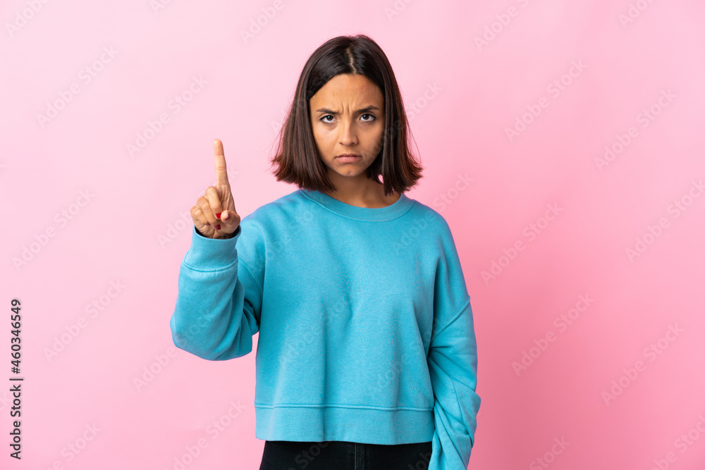 Young latin woman isolated on pink background counting one with serious expression