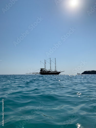Sailing boat on the high seas. The yacht sails along the seashore. Small ship against the blue sky