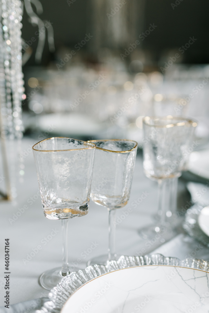 glasses of triangular shape on a set table. Plates and glasses are placed on the table. Festive table decor